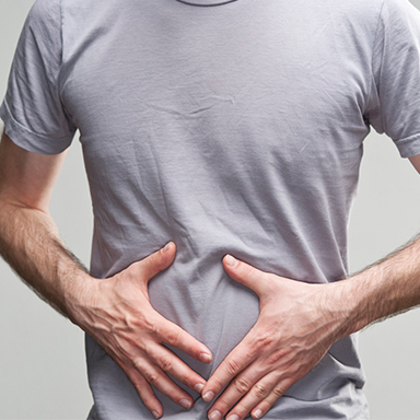 Man holding stomach, Improve digestion with Chiropractic Care Cloverfield